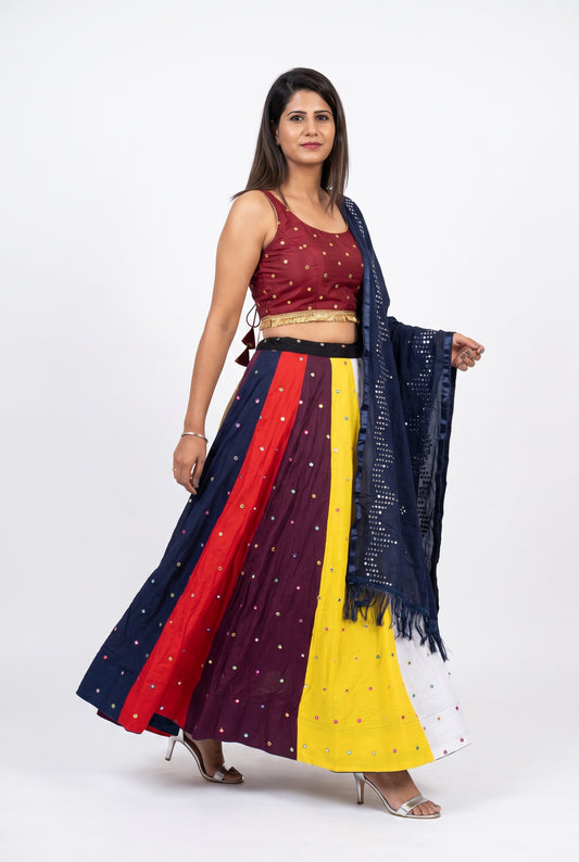 A set of traditional Indian flared skirts or lehengas with matching embroidered blouses, laid out on a white shag rug. The set includes multiple color options: red with gold embroidery, navy blue with silver mirror work, red, purple, yellow, and white with silver mirror work.