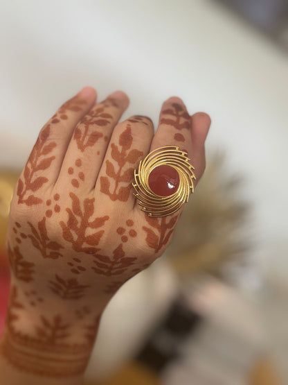 Gold plated ring with a red stone on a hand with henna designs.