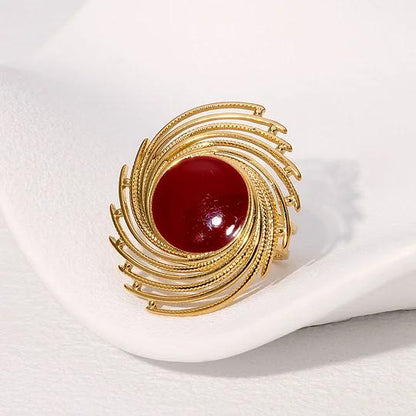 Gold brooch with a red central stone on a white background