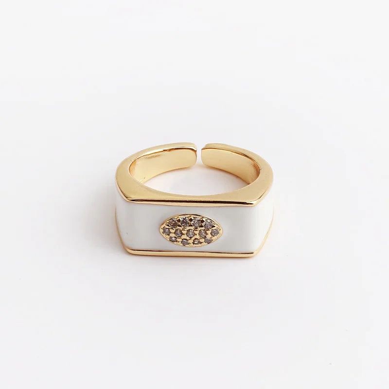 Gold and white ring with a decorative element on a light gray background