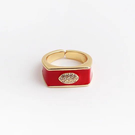 Gold and red ring with a decorative element on a light gray background