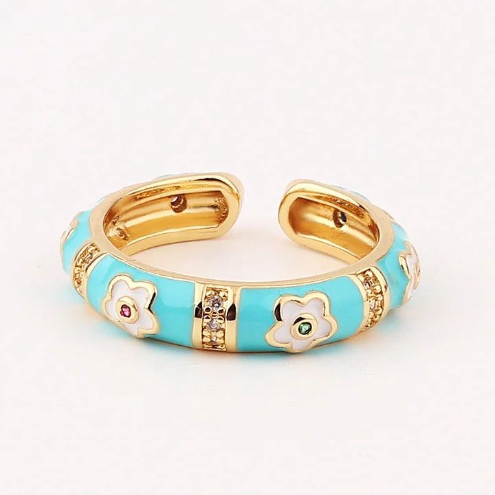 Gold and turquoise ring with floral designs on a white background