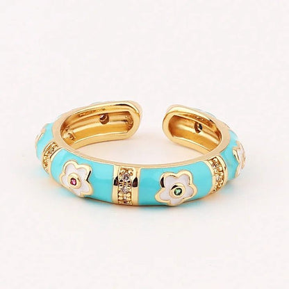 Gold and turquoise ring with floral designs on a white background