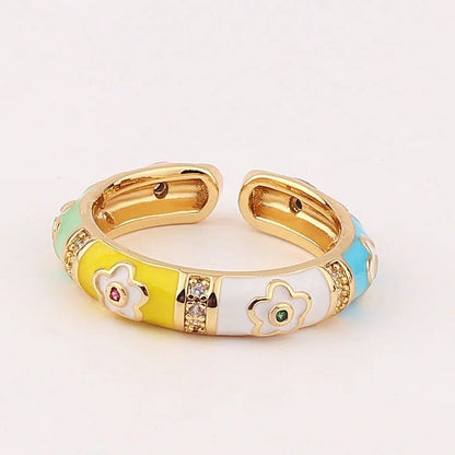 Gold ring with colorful floral designs on a light gray background