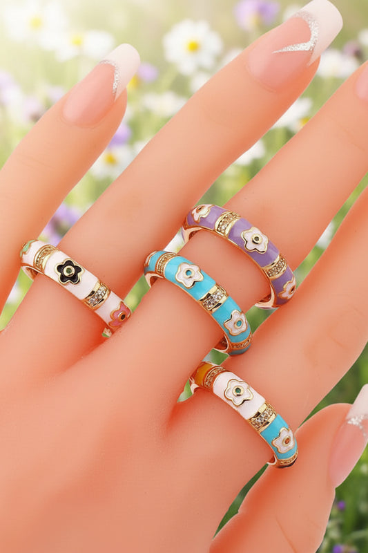 Colorful floral-patterned rings on a hand against a white background